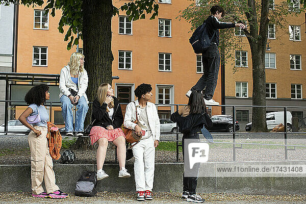 Weibliche und männliche Freunde betrachten einen Teenager  der auf einem Geländer läuft