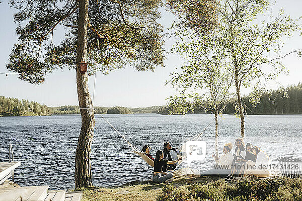Multirassische Freundinnen genießen am Seeufer an einem sonnigen Tag