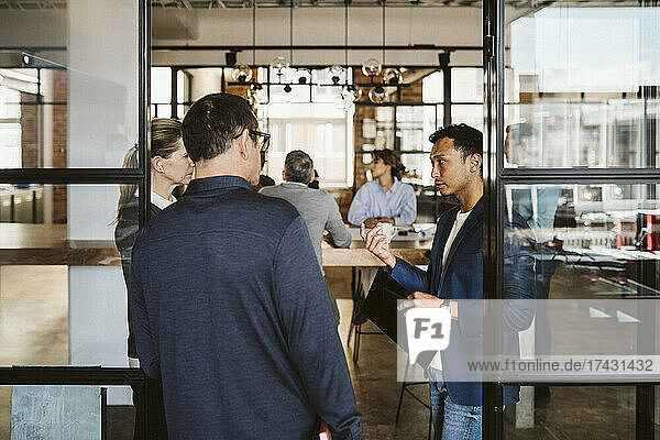 Business people discussing while standing at doorway