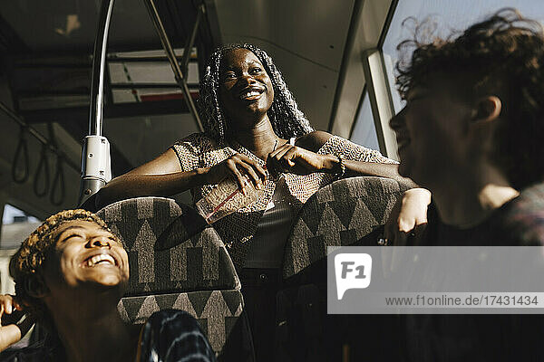 Glückliche multirassische LGBTQIA-Freunde im Bus an einem sonnigen Tag