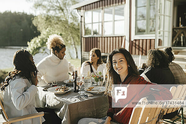 Porträt einer Frau mit Freundinnen beim Essen auf einer Party an einem sonnigen Tag