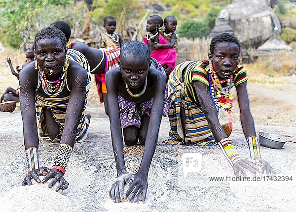 Junge Mädchen mahlen Sorghum auf einem Felsen  Stamm der Laarim  Boya Hills  Ost-Äquatoria  Südsudan  Afrika