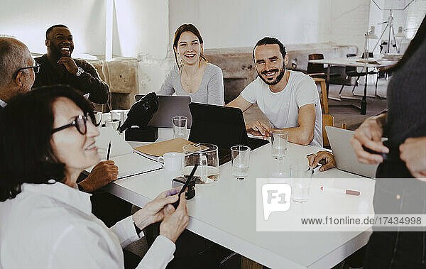 Smiling male and female investors in discussion during meeting at startup company