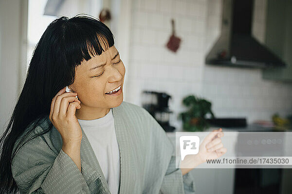 Fröhliche junge Frau singt beim Musikhören zu Hause