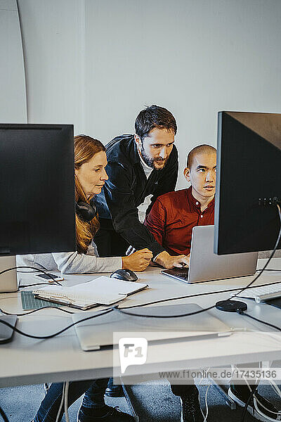 Männlicher Programmierer beim Programmieren mit Kollegen in einem Startup-Unternehmen