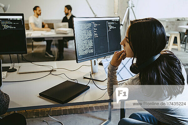 Weiblicher Hacker  der bei der Arbeit in einem Startup-Unternehmen auf einen Computer schaut