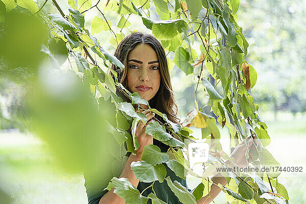 Beautiful young woman amidst branches at park