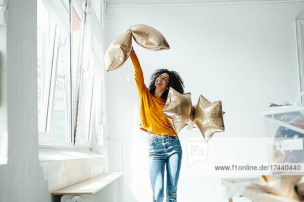 Happy woman holding foil balloons at home