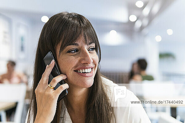 Happy businesswoman talking on smart phone in restaurant