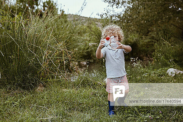 Boy collecting plastics on meadow