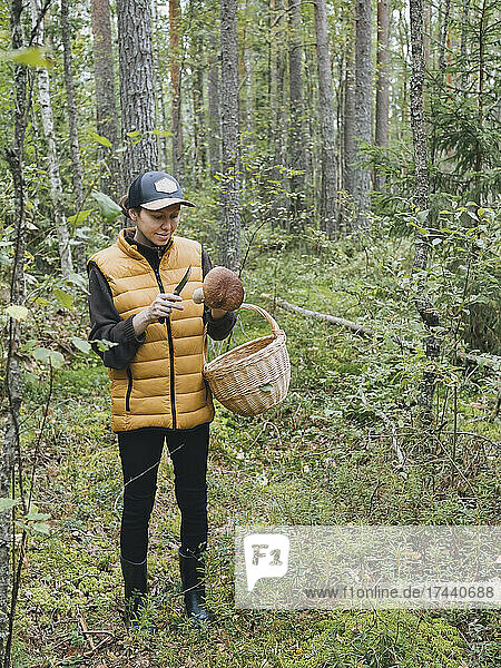 Woman with basket holding mushroom in forest