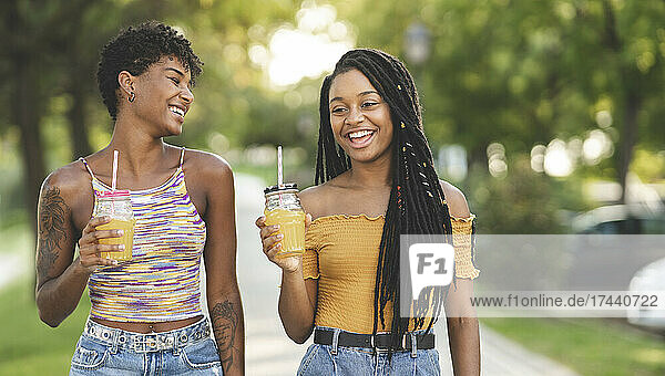 Cheerful women enjoying juice in park