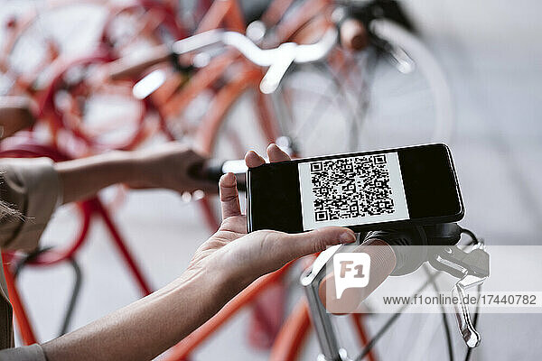 Businesswoman unlocking bicycle through smart phone at parking station
