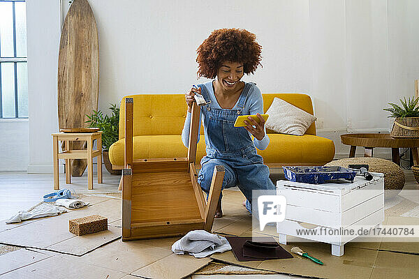 Redhead Afro woman with old chair using smart phone at home