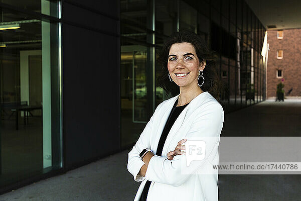 Smiling confident businesswoman standing with arms crossed