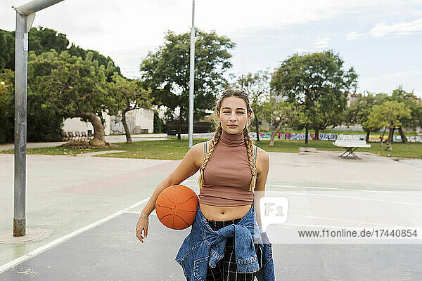 Junge Frau mit Basketball am Sportplatz