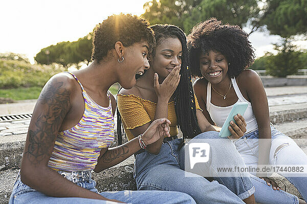 Surprised female friends looking at mobile phone in park