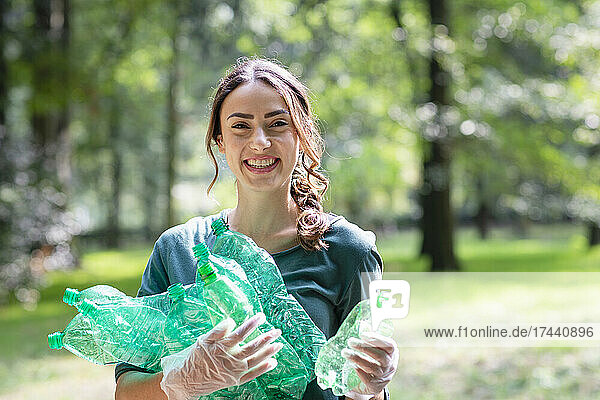 Lächelnde Umweltschützerin sammelt Plastikflaschen im Park