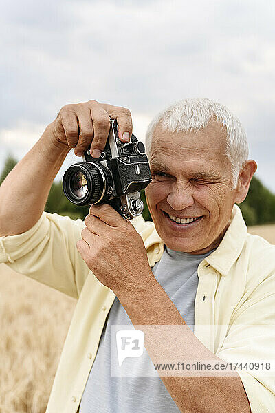 Happy senior man photographing through camera