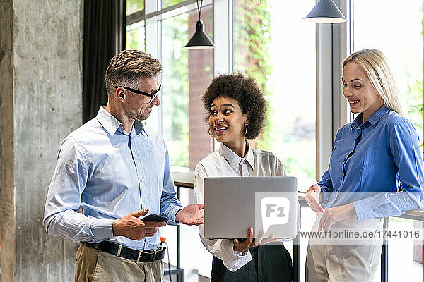 Männliche und weibliche Kollegen diskutieren während der Arbeit im Büro am Laptop