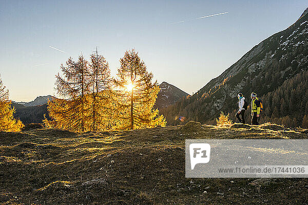 Two people hiking in Ennstal Alps at autumn sunset