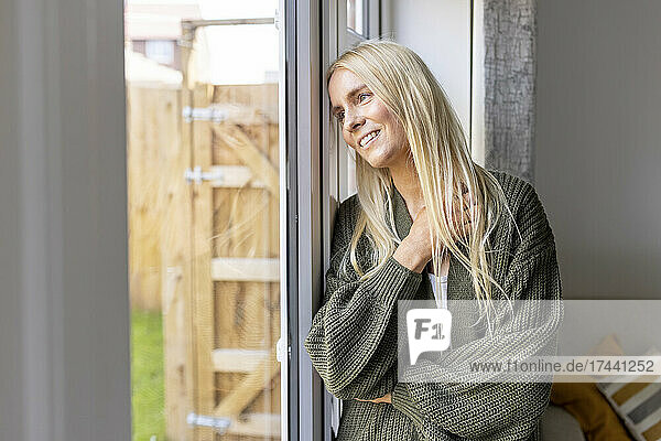 Blond woman looking through glass door