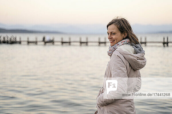 Smiling mid adult woman standing near sea during weekend