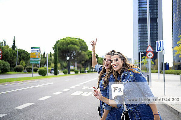 Smiling twin sisters standing on road in city