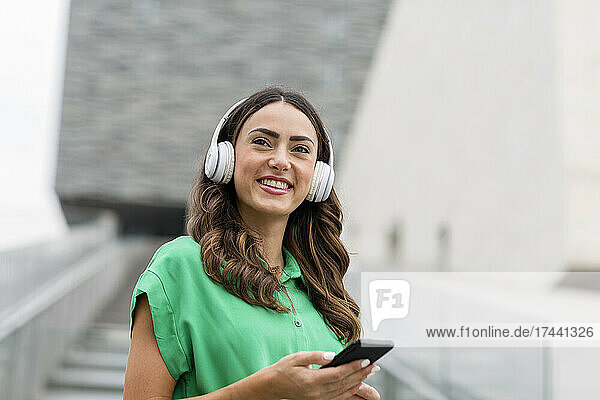Smiling woman with wireless headphones and mobile phone