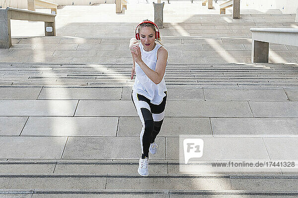 Female athlete with headphones running on staircase