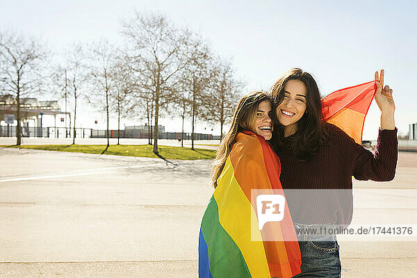 Young lesbian couple with rainbow flag during sunny day