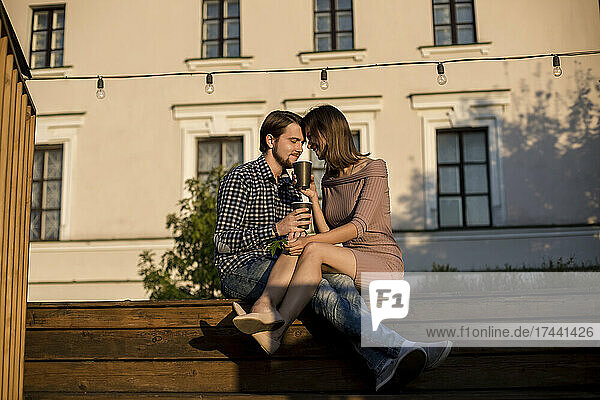 Paar trinkt etwas  während es zusammen auf einer Treppe sitzt