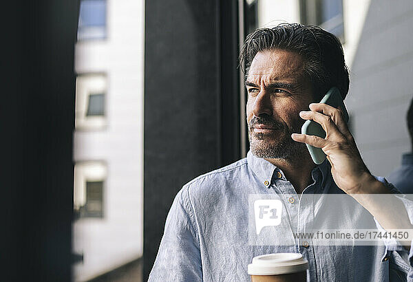 Männlicher Berufstätiger telefoniert beim Kaffeetrinken im Hotelzimmer