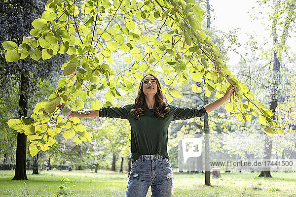 Smiling woman holding branches at park