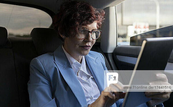 Mature businesswoman using digital tablet while sitting in car