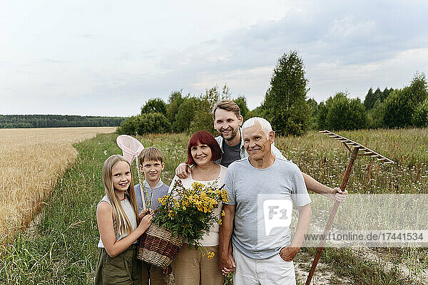 Glückliche Familie mit Blumen und Rechen auf dem Feld