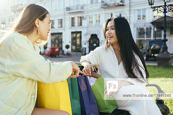 Female friends sitting with shopping bags on bench