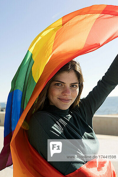 Lächelnde lesbische Frau mit Regenbogenfahne