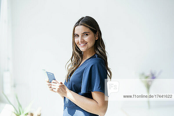 Smiling female architect holding color swatch in office