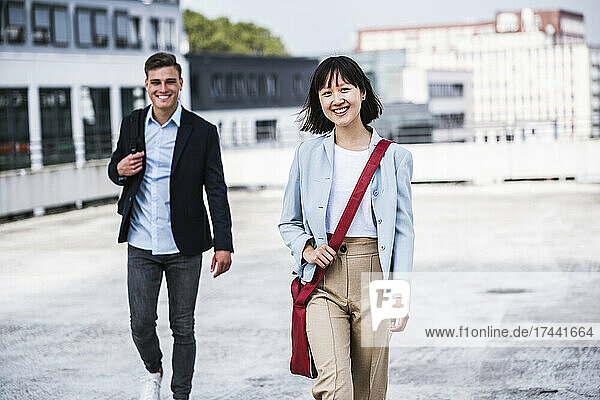 Smiling businesswoman walking with male colleague on rooftop