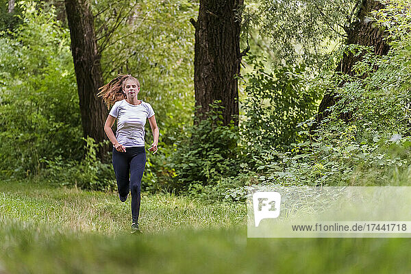Young sportswoman running in forest