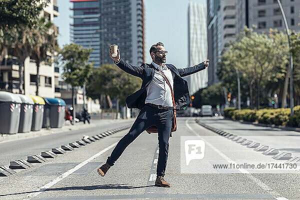 Happy businessman with arms outstretched dancing on street