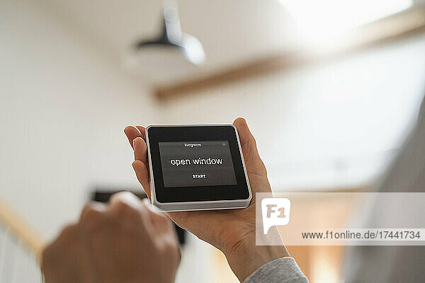 Mid adult woman holding smart home automation device with text