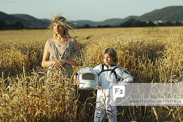 Mother standing with son wearing space suit at field