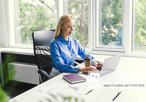 Blond businesswoman using laptop while working in office
