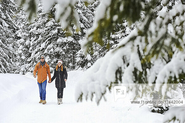 Man and woman enjoying leisure time while walking on snow during winter