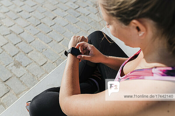 Sportswoman checking time on smart watch during sunny day