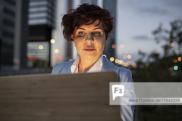 Beautiful mature businesswoman using laptop during dusk