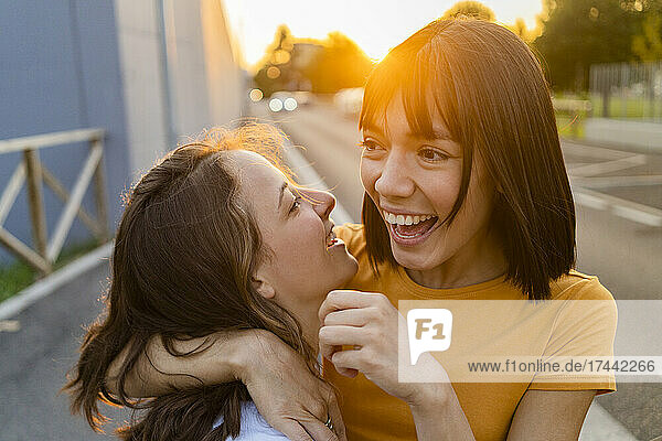 Happy woman with arm around girlfriend during sunset