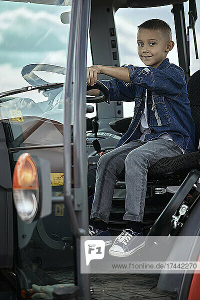 Boy sitting near steering wheel in tractor